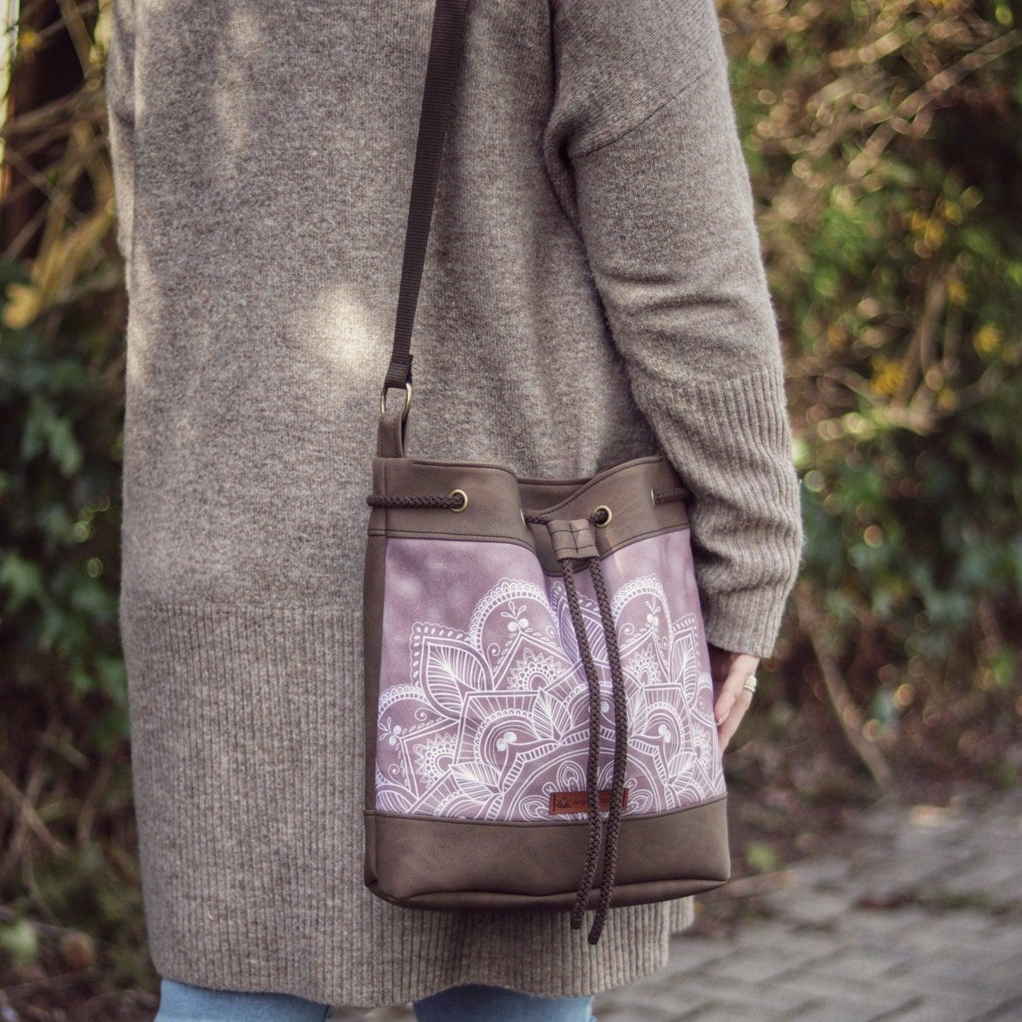 Bucket Bag Handtasche als Schultertasche getragen. Ein dezentes Mandala von AnyArtDesign auf der Vorderseite